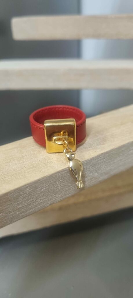 Bague en cuir rouge cousu et bélière carrée dorée avec pampille oiseau