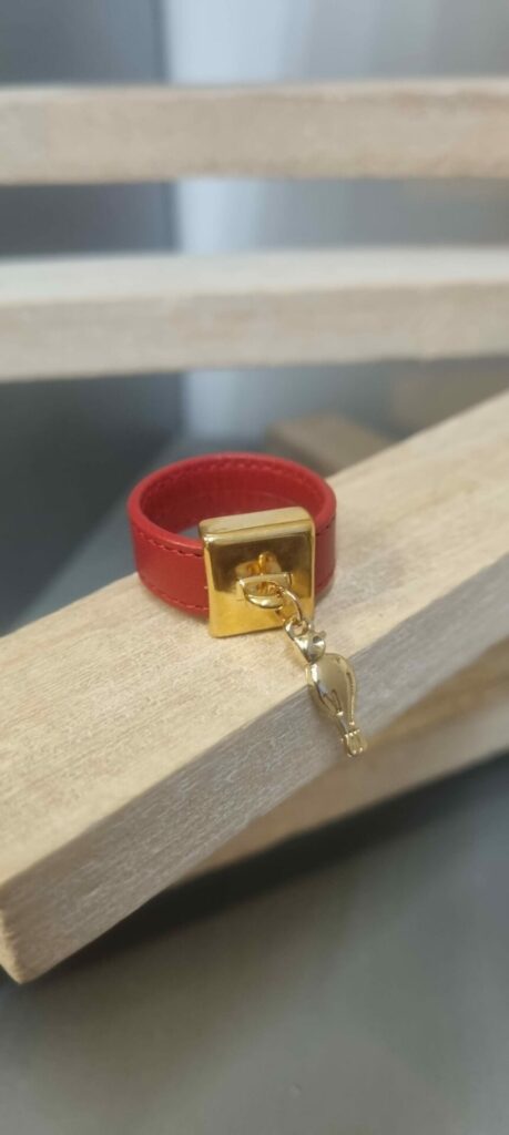 Bague en cuir rouge cousu et bélière carrée dorée avec pampille oiseau