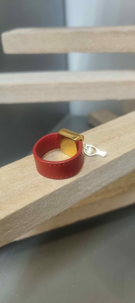 Bague en cuir rouge cousu et bélière carrée dorée avec pampille oiseau