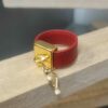 Bague en cuir rouge cousu et bélière carrée dorée avec pampille oiseau