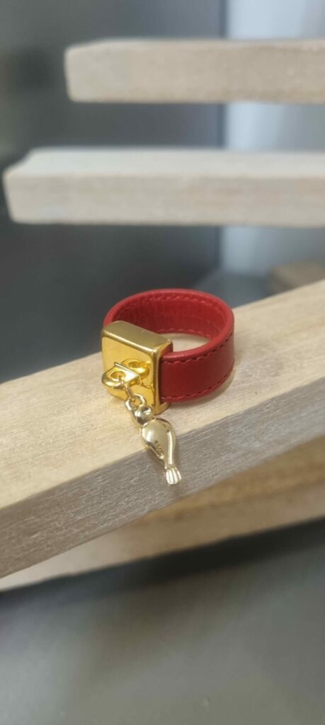 Bague en cuir rouge cousu et bélière carrée dorée avec pampille oiseau